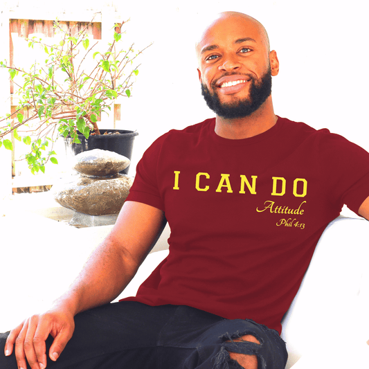 Man wearing a maroon t-shirt with 'I CAN DO Attitude Phil 4:13' text,by marto and tshirts, sitting in a room with plants.